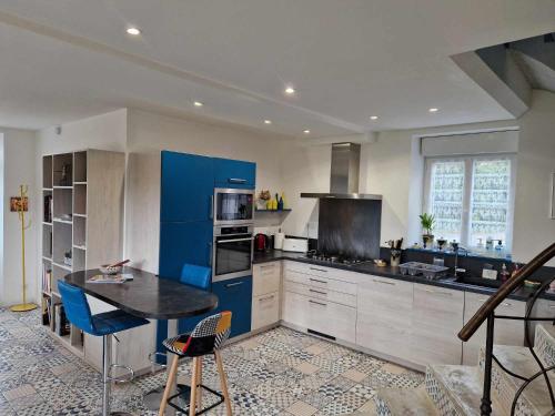 d'une cuisine avec des placards bleus et une table. dans l'établissement Coeur de Reigny, à Les Epsailles