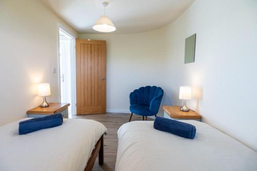 a room with two beds and a blue chair at Glan Yr Afon in Llanrhyddlad