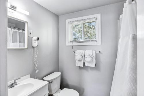 baño con aseo y lavabo y ventana en Ocean Breeze Motel en South Yarmouth