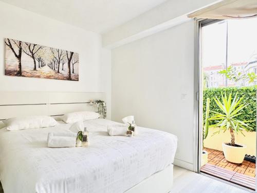 une chambre blanche avec un lit et une grande fenêtre dans l'établissement L’éclat - Appartement terrasse - Centre Cannes, à Cannes