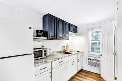 a kitchen with white cabinets and a white refrigerator at Ocean Breeze Motel in South Yarmouth