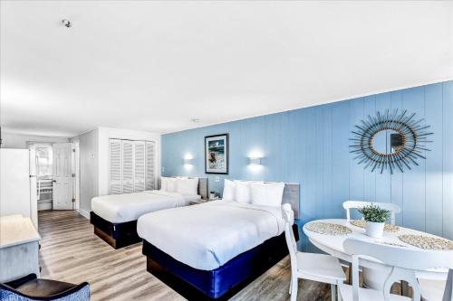 Habitación de hotel con 2 camas y mesa en Ocean Breeze Motel en South Yarmouth