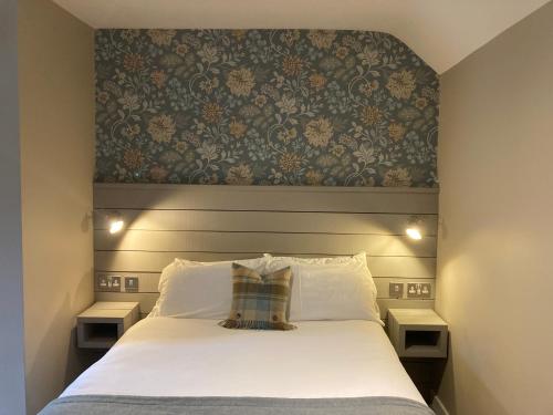 una camera da letto con un grande letto bianco con testiera del letto di West Port Hotel a Linlithgow