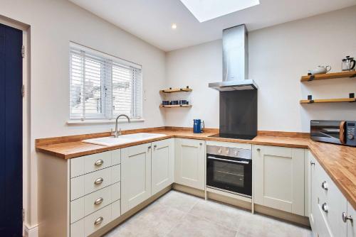 a kitchen with white cabinets and a sink at Host & Stay - Porter Cottage in Alnwick