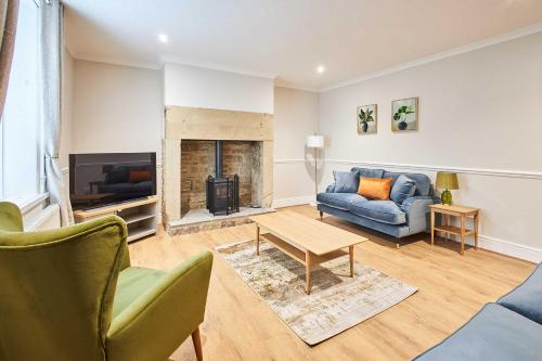 a living room with a blue couch and a fireplace at Host & Stay - Porter Cottage in Alnwick