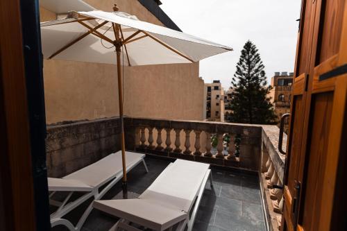 a balcony with two chairs and an umbrella at Penthouse Suite 9 at Palazzo Seraphim Boutique living in St Julians in St. Julianʼs