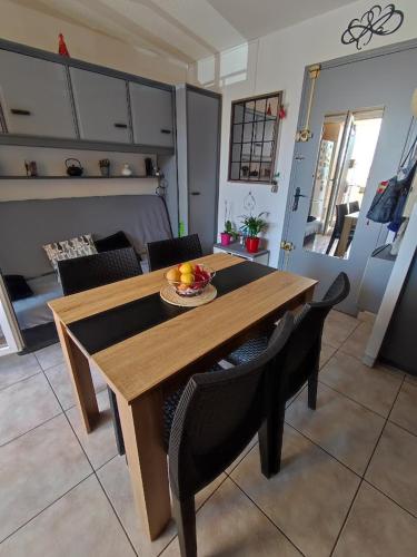 - une table en bois avec des chaises et une corbeille de fruits dans l'établissement Charmant appartement à Sainte Marie la mer (66470), à Sainte-Marie-Plage