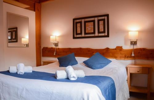 a bedroom with a large white bed with blue pillows at Apart Hotel del Pellin in San Martín de los Andes