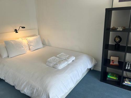 1 cama con sábanas blancas y almohadas en una habitación en Hermitage accomodation en Londres