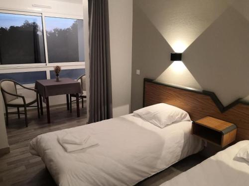 a hotel room with a bed and a table and a window at La Canotte in Saint-Julien-en-Born