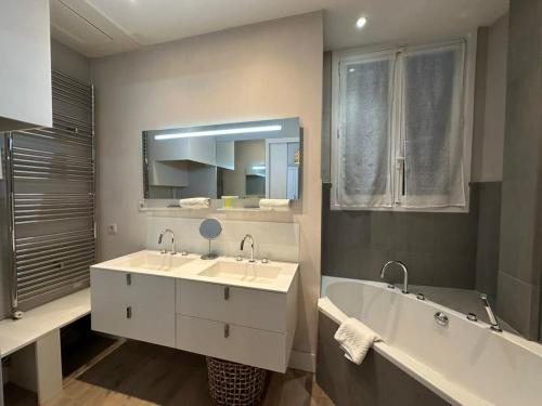 une salle de bain avec deux lavabos, une baignoire et un miroir dans l'établissement C025 Villa Toscane Bel Appartement Bourgeois, à Cannes