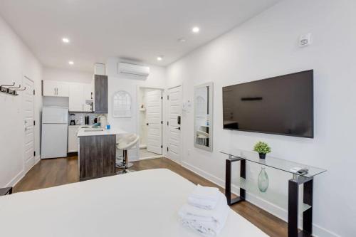 a kitchen with white walls and a large flat screen tv at Le Mile End by M11 - Upscale Studio with Queen Bed in Montréal