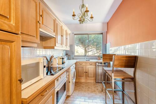 une grande cuisine avec des placards en bois et une fenêtre dans l'établissement L'Étrier-Cannes Centre Terrasse, à Cannes