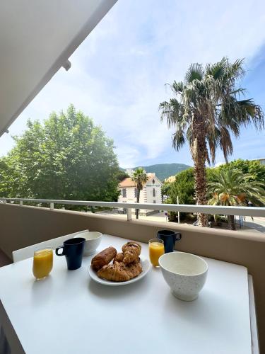 une table avec deux assiettes de nourriture sur un balcon dans l'établissement Appartement 2 pièces Cavalaire sur Mer 60m2, à Cavalaire-sur-Mer