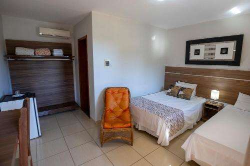 una camera d'albergo con letto e sedia di Hotel Pousada das Flores a Cordisburgo