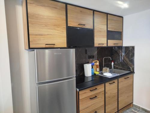 a kitchen with wooden cabinets and a stainless steel refrigerator at Christy's apartment by the sea in Skála Foúrkas