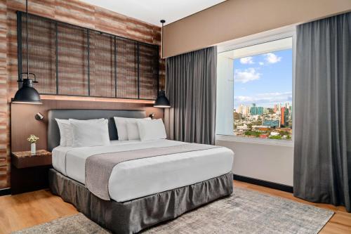 a bedroom with a large bed and a large window at NH Collection Monterrey San Pedro in Monterrey