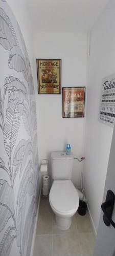 baño con aseo y 2 cuadros en la pared en Le manège terre et mer proche Etretat, en Gonneville-la-Mallet