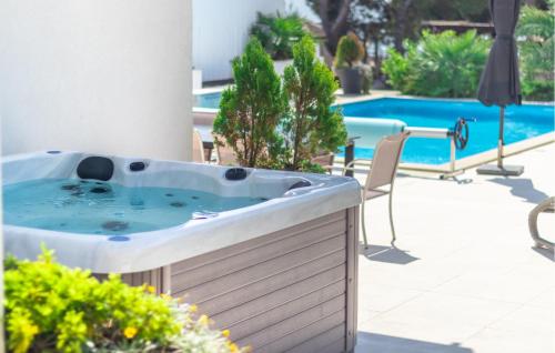 a hot tub on a patio next to a pool at Beach Front Home In Punat With Kitchen in Punat