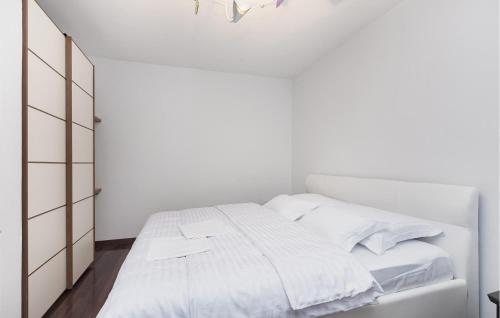 a white bedroom with a bed with white sheets at Beach Front Home In Punat With Kitchen in Punat