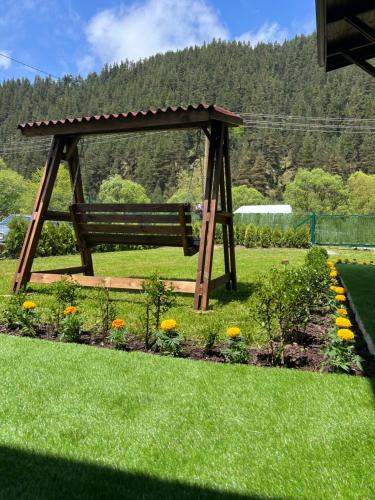 a wooden bench in a garden with flowers at Guest House Recharge in Govedartsi