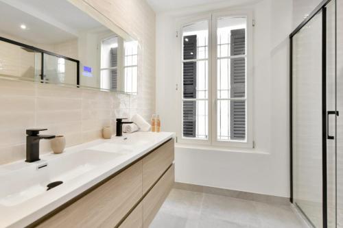 un bagno bianco con lavandino e specchio di Villa Léon - Centre Cannes - 4 chambres - Clim a Cannes