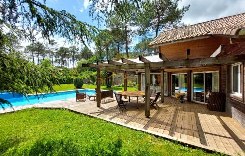 a wooden patio with a table and a pool at Stunning Home In Seignosse in Seignosse