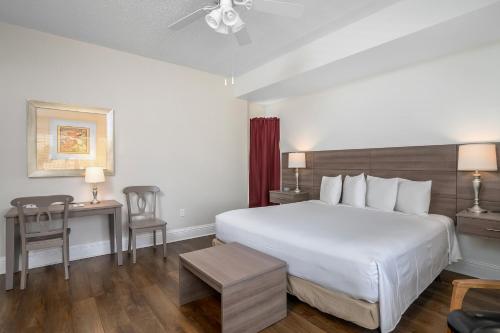 a hotel room with a white bed and a table at Naples Park Central Hotel in Naples