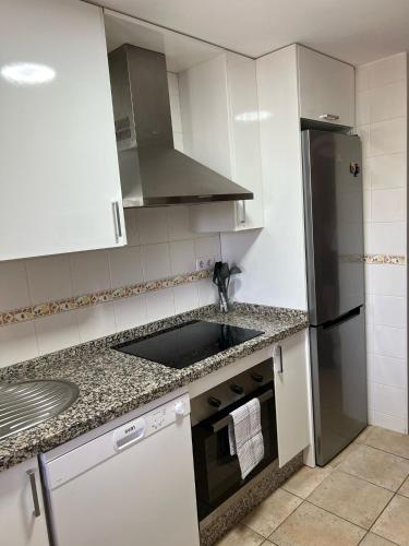 a kitchen with white cabinets and a black refrigerator at Esuri Relax & Golf in Ayamonte