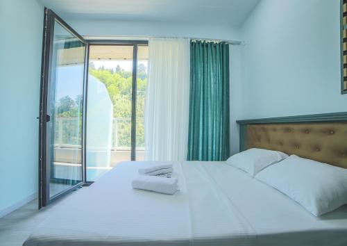a bedroom with a large white bed with a window at Bamboo Beach Cixisdziri in Tsikhisdziri