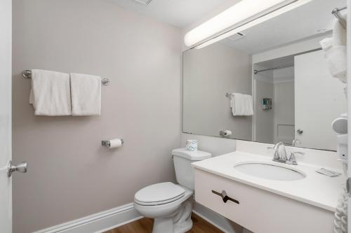 a white bathroom with a toilet and a sink at Naples Park Central Hotel in Naples