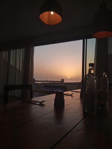 a bottle on a table with a view of the ocean at Loued Surf Lodge in Imsouane