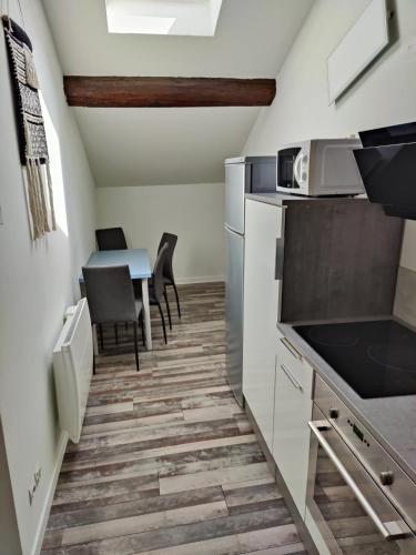 una cocina con armarios blancos y una mesa con sillas. en L'ancre de la Seille en Château-Salins
