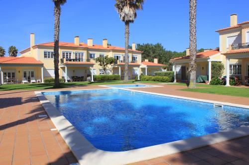 a swimming pool in front of a house with palm trees at D. Sebastião Townhouse in Casal da Lagoa Seca