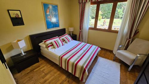 ein Schlafzimmer mit einem Bett und einem Stuhl und einem Fenster in der Unterkunft CASA MEXILLOEIRA in O Grove