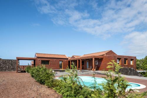 uma casa com uma piscina em frente em Alma do Pico - Nature Residence em Madalena