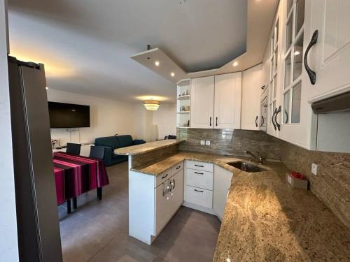 une cuisine avec des armoires blanches et un salon dans l'établissement C058 Bel appartement spacieux terrasse Centre, à Cannes