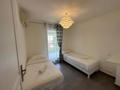 une chambre avec deux lits et un lustre dans l'établissement C058 Bel appartement spacieux terrasse Centre, à Cannes