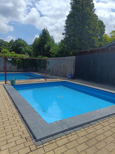 a small blue swimming pool with a fence at Vakantiehuisje Veluwe, Alleen Voor Recreatie in Putten