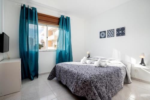a bedroom with a bed with blue curtains and a window at Blife Allya private rooms in Faro