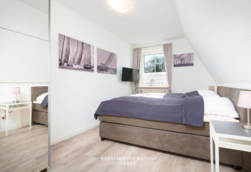 a white bedroom with a bed and a desk at Appartement-Service-Laboe in Laboe