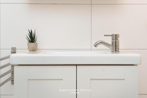 - un lavabo blanc dans la salle de bains avec une plante en pot dans l'établissement Appartement-Service-Laboe, à Laboe