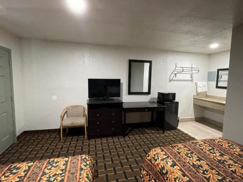 エイダにあるBudget Inn Adaのデスクとベッドが備わるホテルルームです。