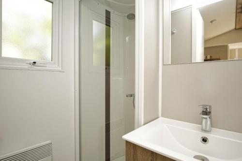 a white bathroom with a sink and a shower at Tiny Chalet Nr 814 in Göhren