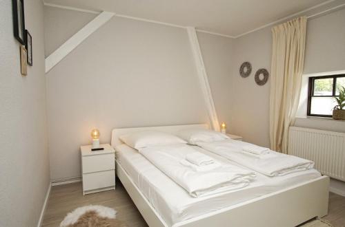 a white bedroom with a bed and a window at Haus Büdnerstube Ferienwohnung Nr 3 - mit Schwimmbad und Saunanutzung im AHOI-Erlebnisbad Sellin in Middelhagen