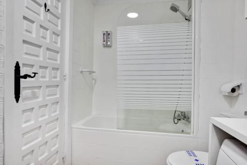 uma casa de banho branca com uma banheira e um chuveiro em Edificio Carihuela By IVI Real Estate em Torremolinos