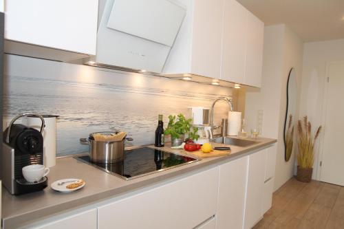 a kitchen with white cabinets and a stove top oven at Sieltied in Greetsiel