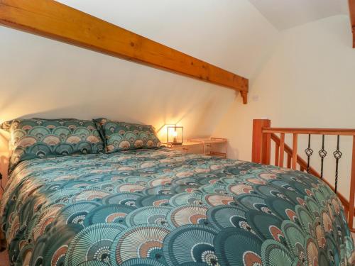 a bedroom with a bed with a green comforter at Harvest Moon Cottage in Bishops Frome