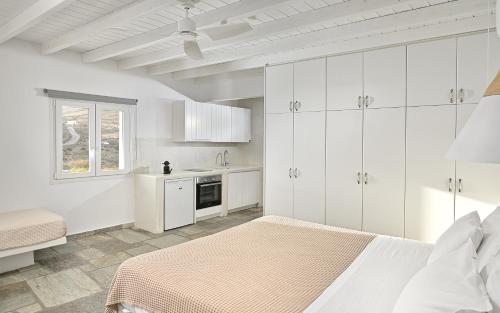 a white bedroom with a bed and a kitchen at VLIA MAR Myconian Residences in Kalafatis