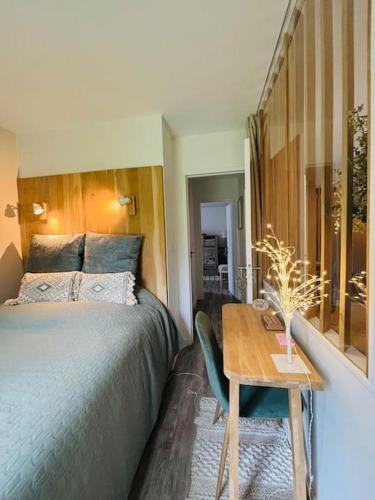 une chambre avec un lit et une table en bois dans l'établissement Le sublime Olivier Normand, 3P cosy et luxe avec jardin, piscine & tennis, vélos, à Deauville